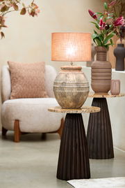 Rustikaler Lampenschirm auf antikem Keramikfuß, seitliche Perspektive, umgeben von moderner Einrichtung und Blumen.