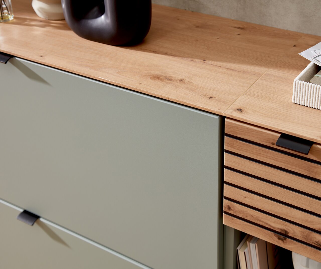 Detailansicht eines Garderoben-Sets mit einer Kombination aus glatten und lamellenartigen Holzoberflächen, in einem modernen Design mit natürlichem Holzton und grünlichen Fronten.