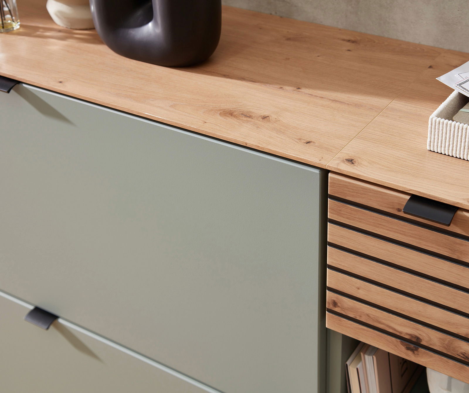 Detailansicht eines Garderoben-Sets mit einer Kombination aus glatten und lamellenartigen Holzoberflächen, in einem modernen Design mit natürlichem Holzton und grünlichen Fronten.