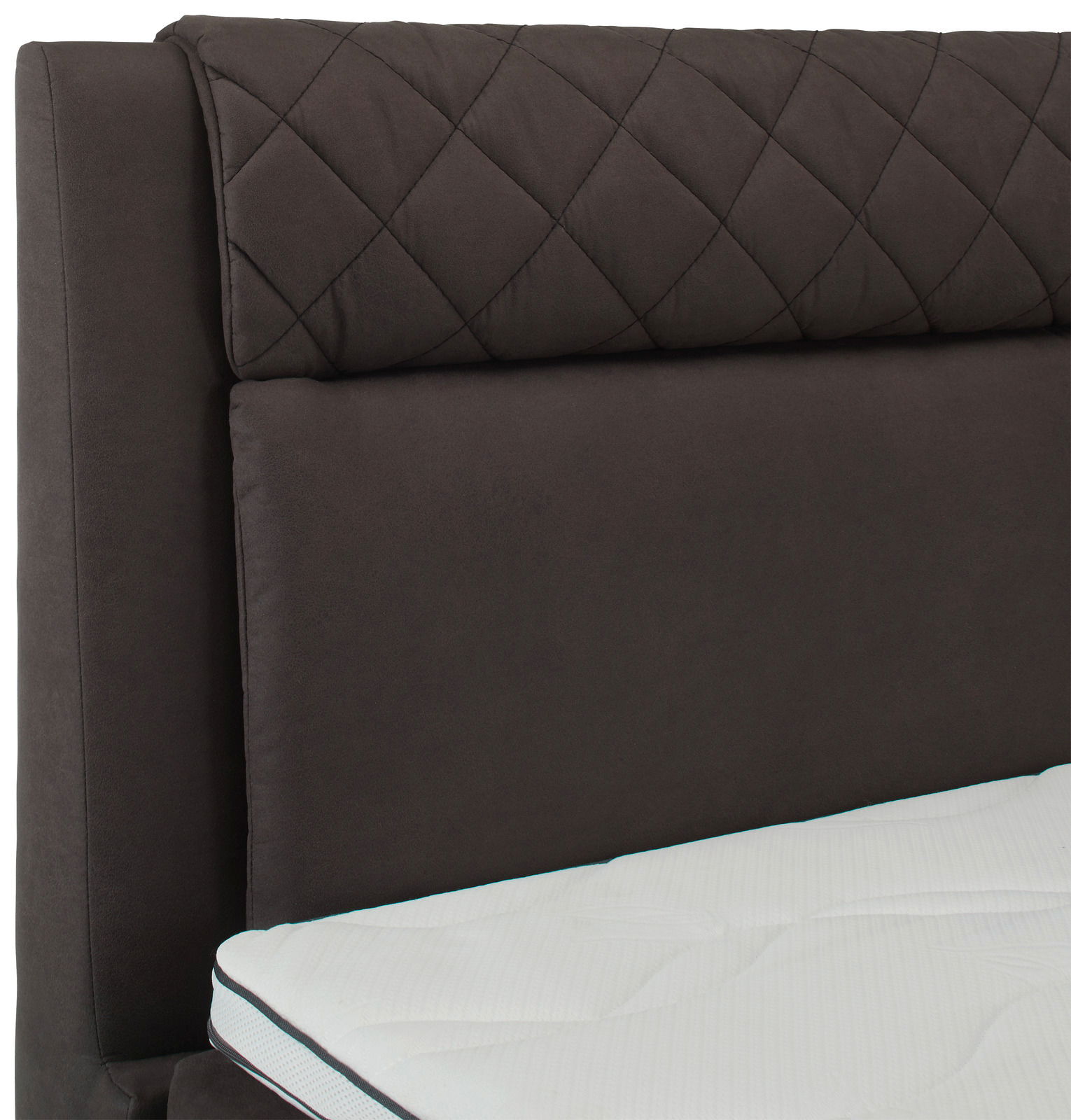 Nahaufnahme eines Boxspringbettes mit gestepptem Kopfteil in dunklem Stoff und weißer Matratze, seitliche Perspektive