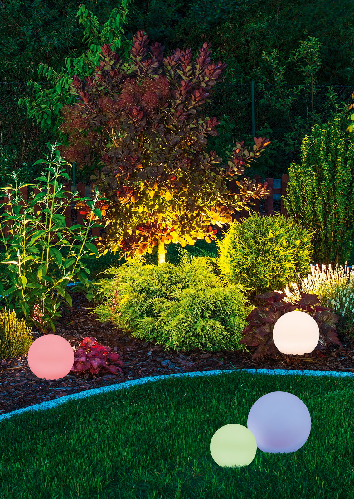 Bunte Solar-Außenleuchten in Kugelform im Garten, aus der Perspektive von vorne.