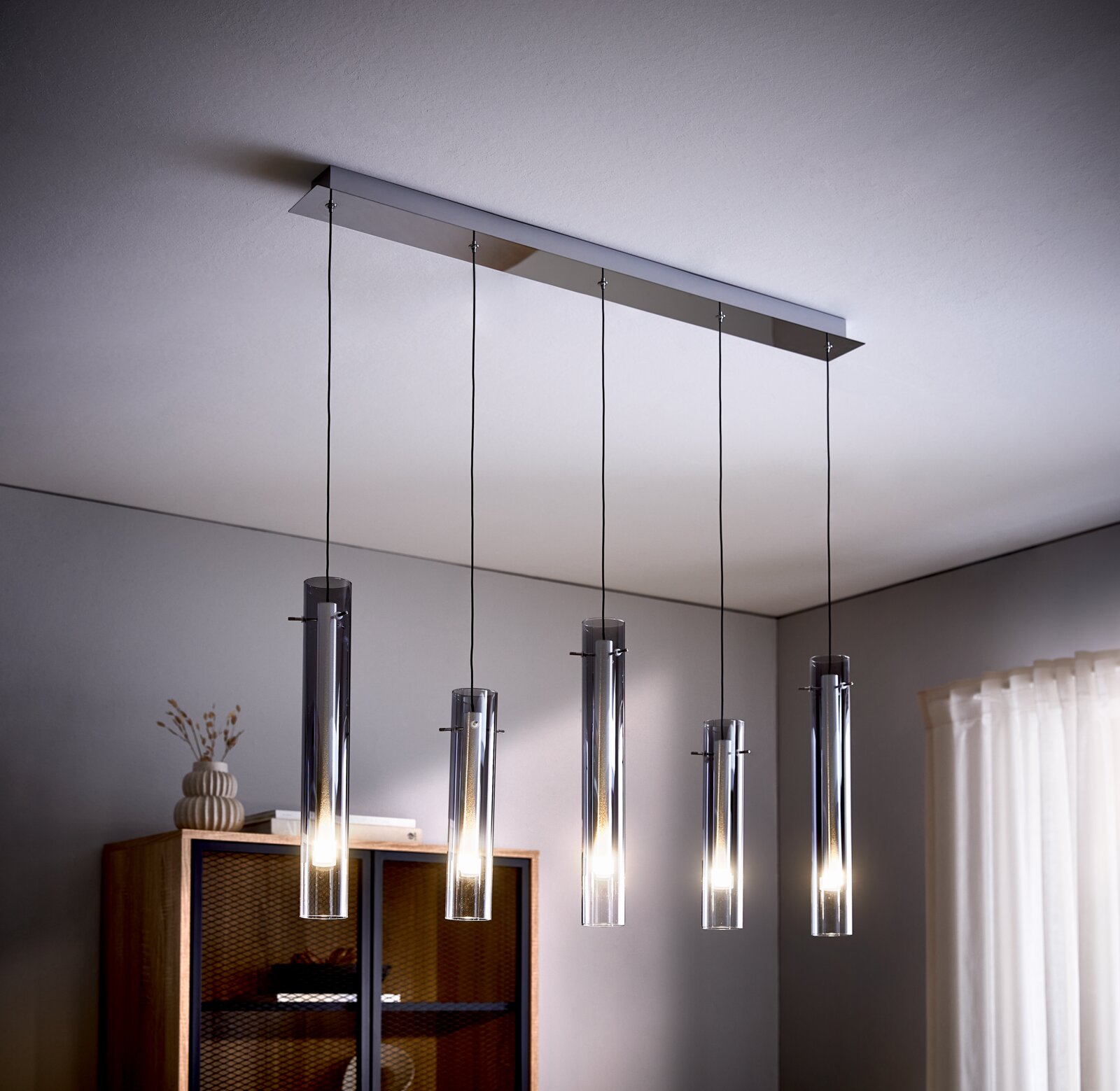 Ambiente LED-Hängeleuchte GLASINI Moderne LED-Hängeleuchte mit fünf zylindrischen Lampen, aufgehängt an dünnen Kabeln, in einem stilvollen Wohnraum von unten betrachtet.