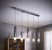 Moderne LED-Hängeleuchte mit fünf zylindrischen Lampen, aufgehängt an dünnen Kabeln, in einem stilvollen Wohnraum von unten betrachtet.