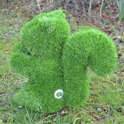 Grüne, grasbedeckte Eichhörnchen-Gartenfigur von der Seite, auf einer Wiese platziert.