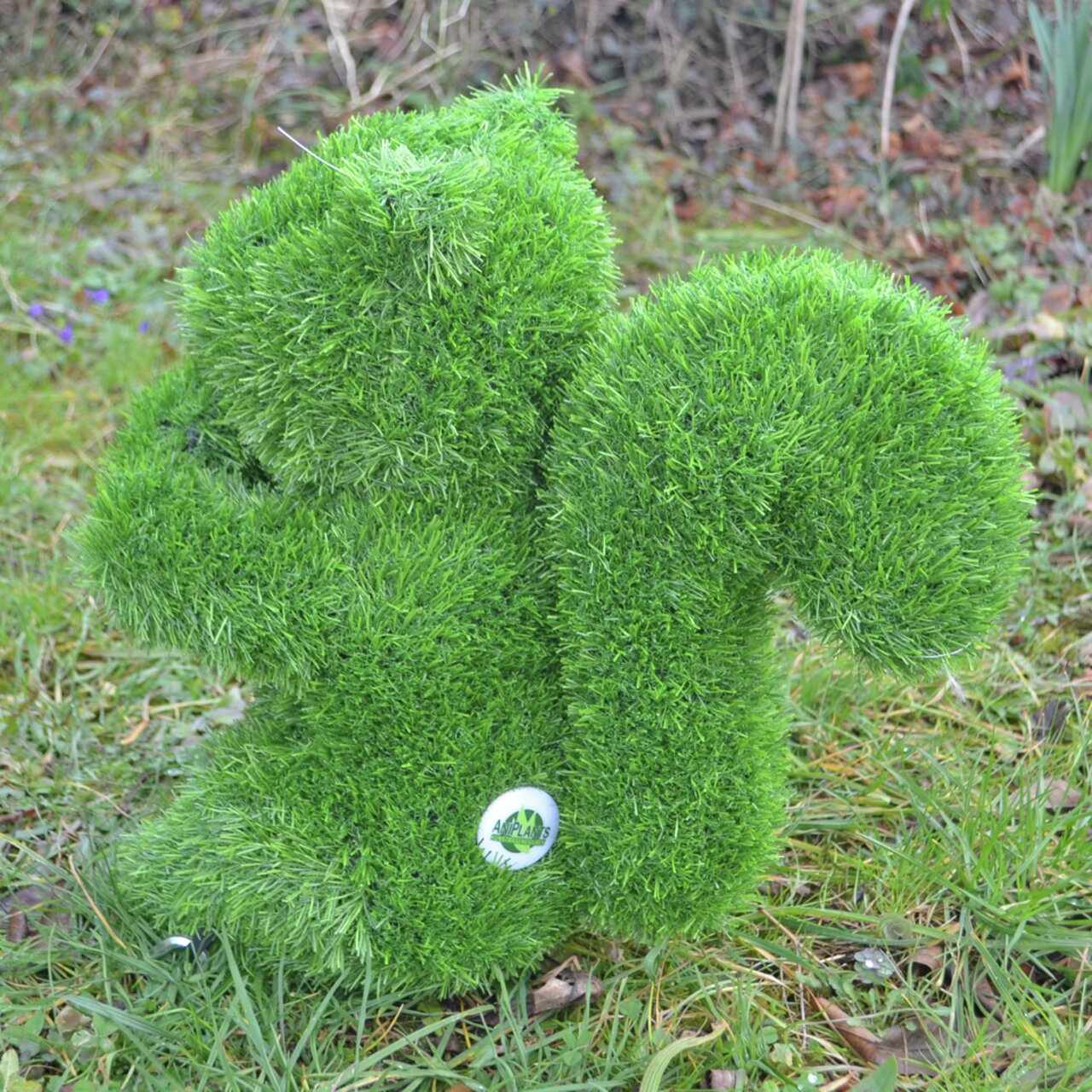 Grüne, grasbedeckte Eichhörnchen-Gartenfigur von der Seite, auf einer Wiese platziert.