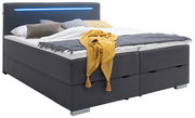 Boxbett mit grauem Stoffbezug, LED-Lichtleiste im Kopfteil und bunter Bettwäsche, seitliche Perspektive