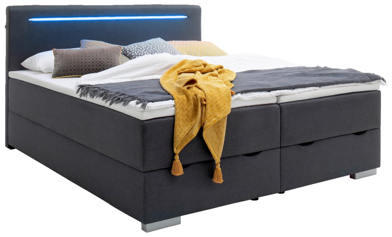 Boxbed met grijze stoffen bekleding, led-verlichtingsstrip in het hoofdeinde en kleurrijk beddengoed, zijaanzicht