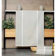 Beige Geschirrtuch mit dezentem Muster, aufgehängt vor einer Holzwand mit Pflanzen im Hintergrund, Vorderansicht