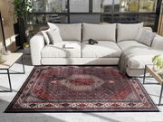 Orientteppich in einem modernen Wohnzimmer, von oben betrachtet, mit einem hellen Sofa und großen Fenstern im Hintergrund.