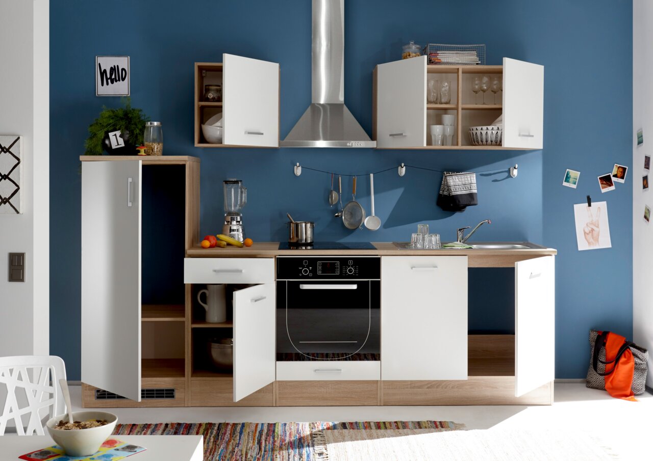 Moderne Küchenzeile mit weißen und holzfarbenen Schränken, Edelstahl-Dunstabzugshaube und blauer Wand im Hintergrund, frontale Perspektive.