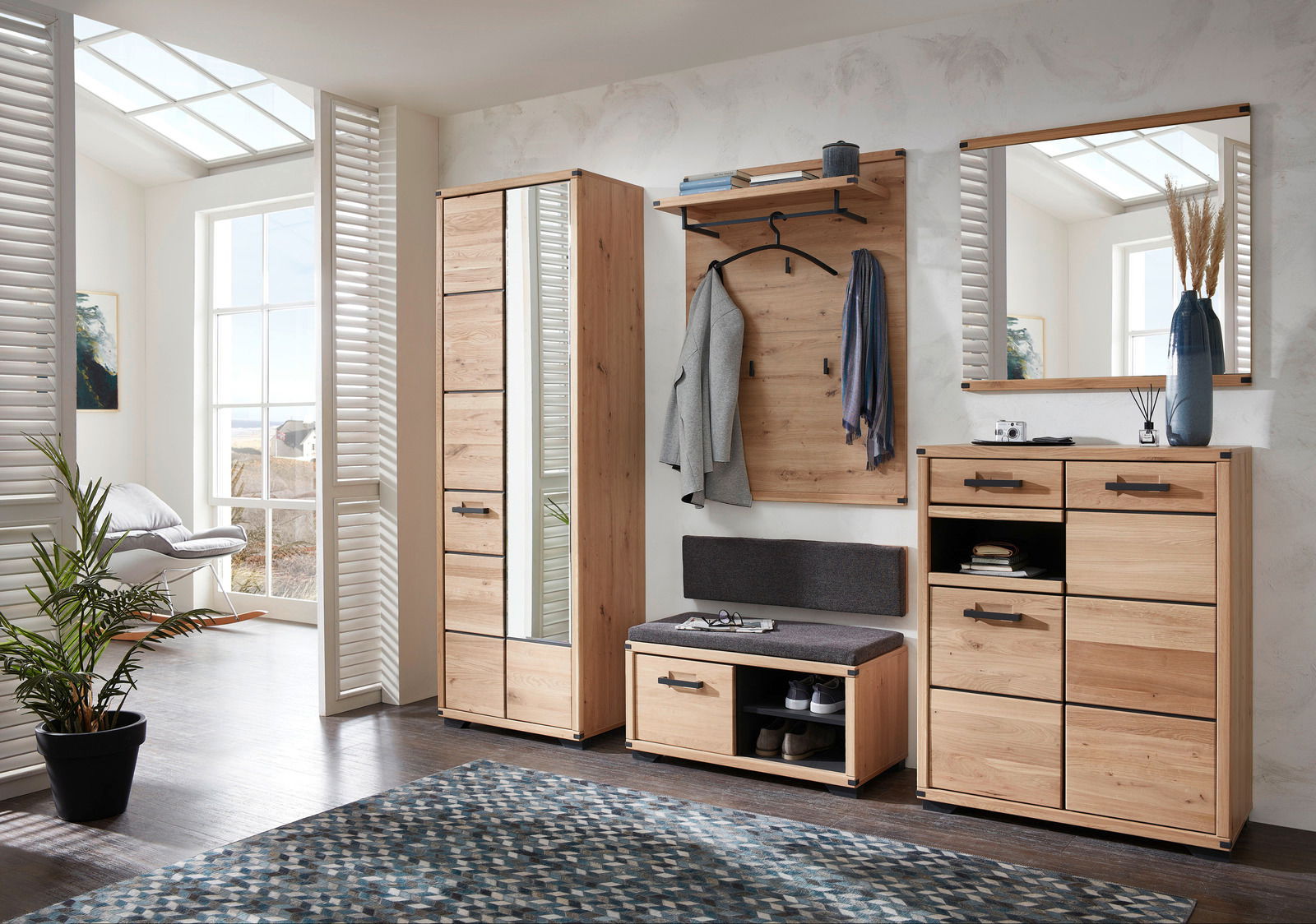 Moderne Garderobeneinrichtung aus Holz mit Garderobenschrank, Schuhschrank, Garderobenpaneel, Spiegel und Garderobenbank in einem hellen Raum mit großen Fenstern, seitliche Perspektive.