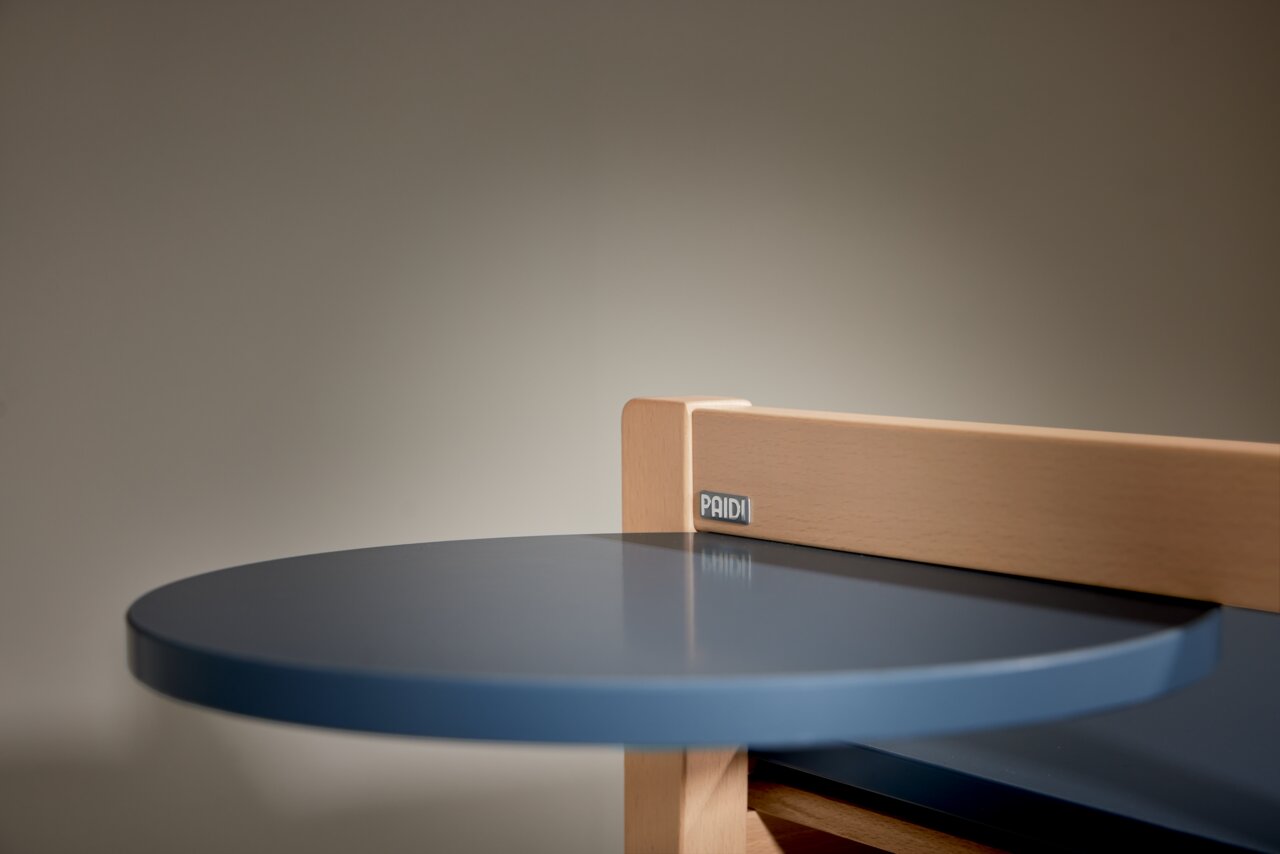 Close-up van een blauwe, ronde tafel met houten frame, gezien vanuit de zijkant