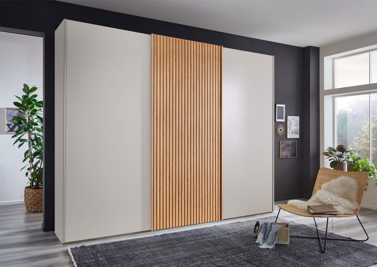 Novel Schwebetürenschrank TEXAS Moderner Schwebetürenschrank mit Holzlamellen-Design in einem stilvoll eingerichteten Raum, seitliche Perspektive.