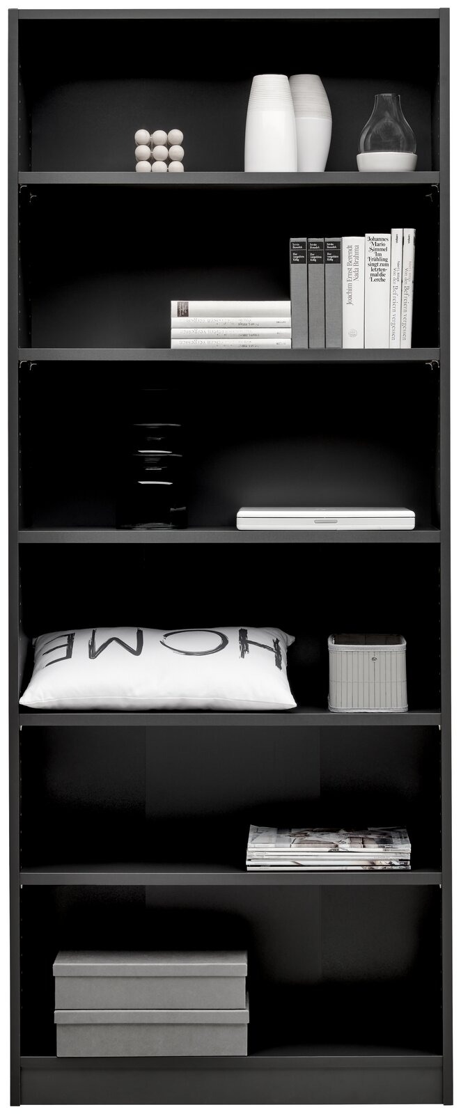 Schwarzes Regal mit mehreren Fächern, gefüllt mit Büchern, Dekorationsgegenständen und Kissen, frontal fotografiert.
