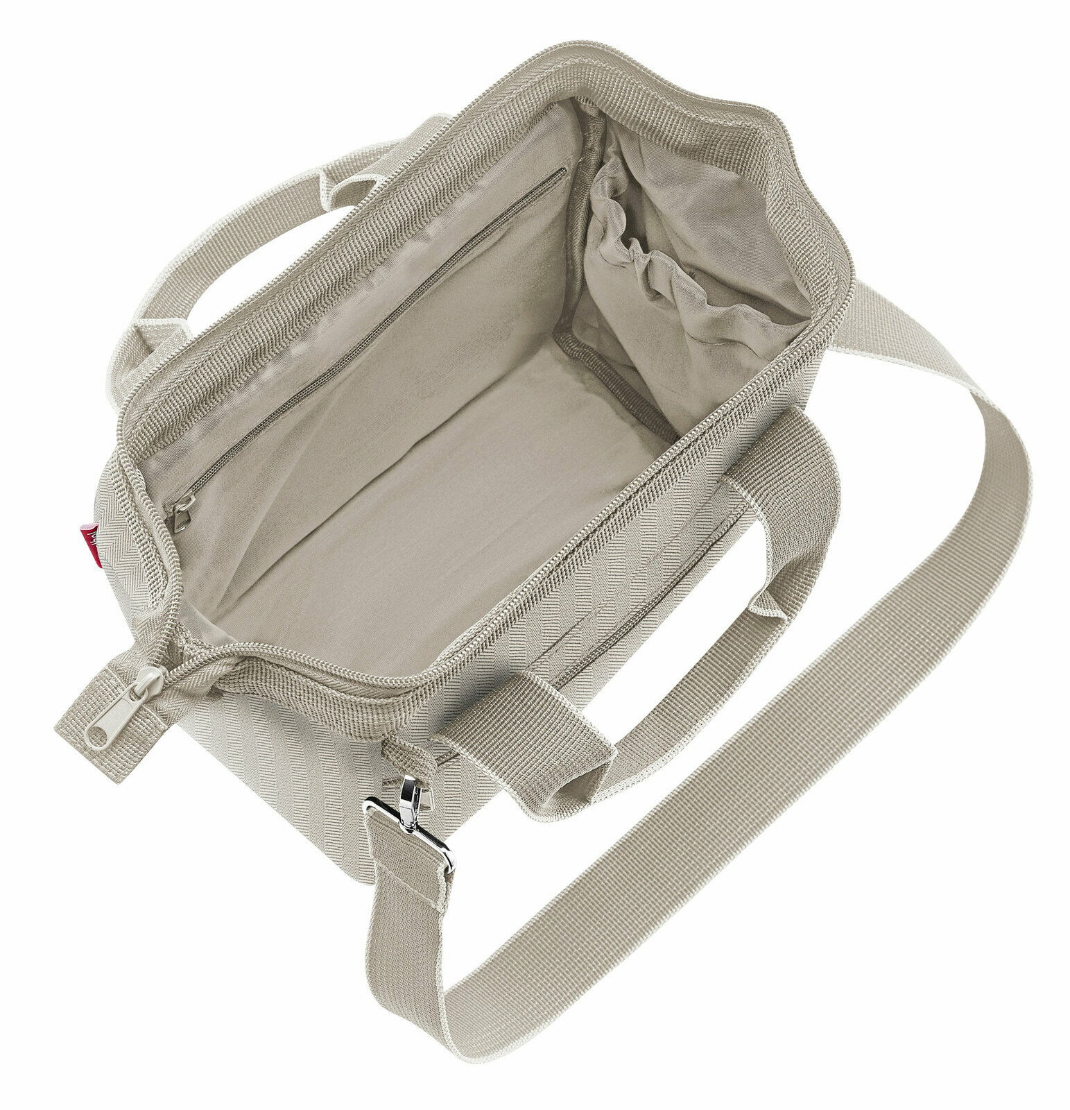 Innenansicht einer beigen Tasche mit Reißverschluss und Schultergurt, von oben fotografiert.