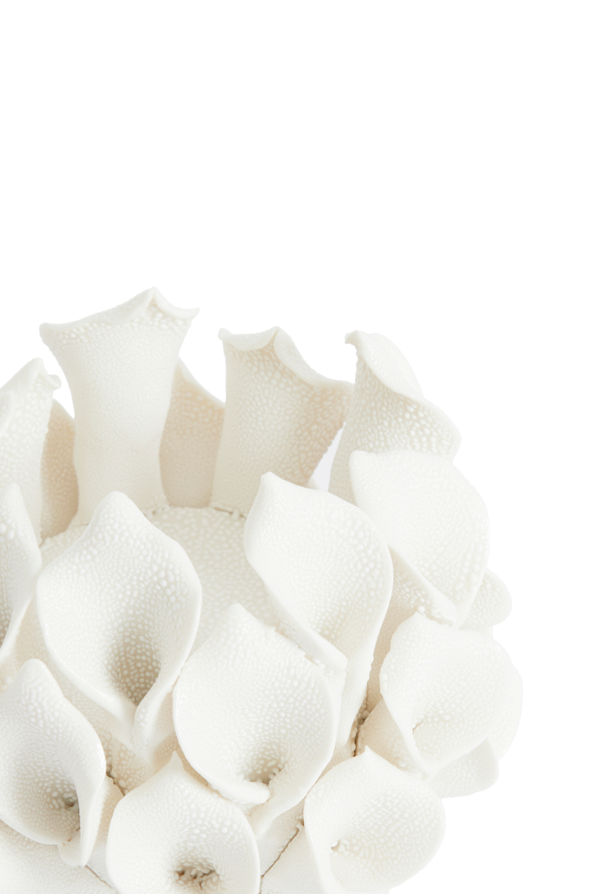 Nahaufnahme eines weißen Teelichthalters mit blütenähnlichen Strukturen, von oben betrachtet.