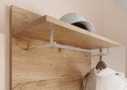 Nahaufnahme eines Garderobenpaneels aus Holz mit einer Ablage und einer Kleiderstange. Auf der Ablage liegt eine Kappe, und an der Stange hängt ein Mantel. Perspektive von schräg unten.