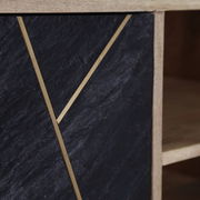 Nahaufnahme eines TV-Lowboards mit schwarzer Steinoptik und goldenen Zierleisten, seitliche Perspektive.