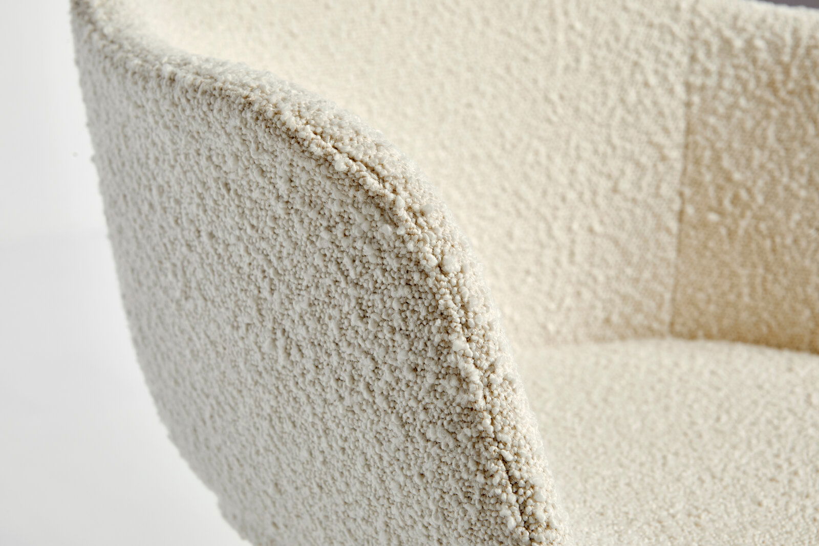 Nahaufnahme eines Stuhls mit strukturierter, cremefarbener Oberfläche, seitliche Perspektive.