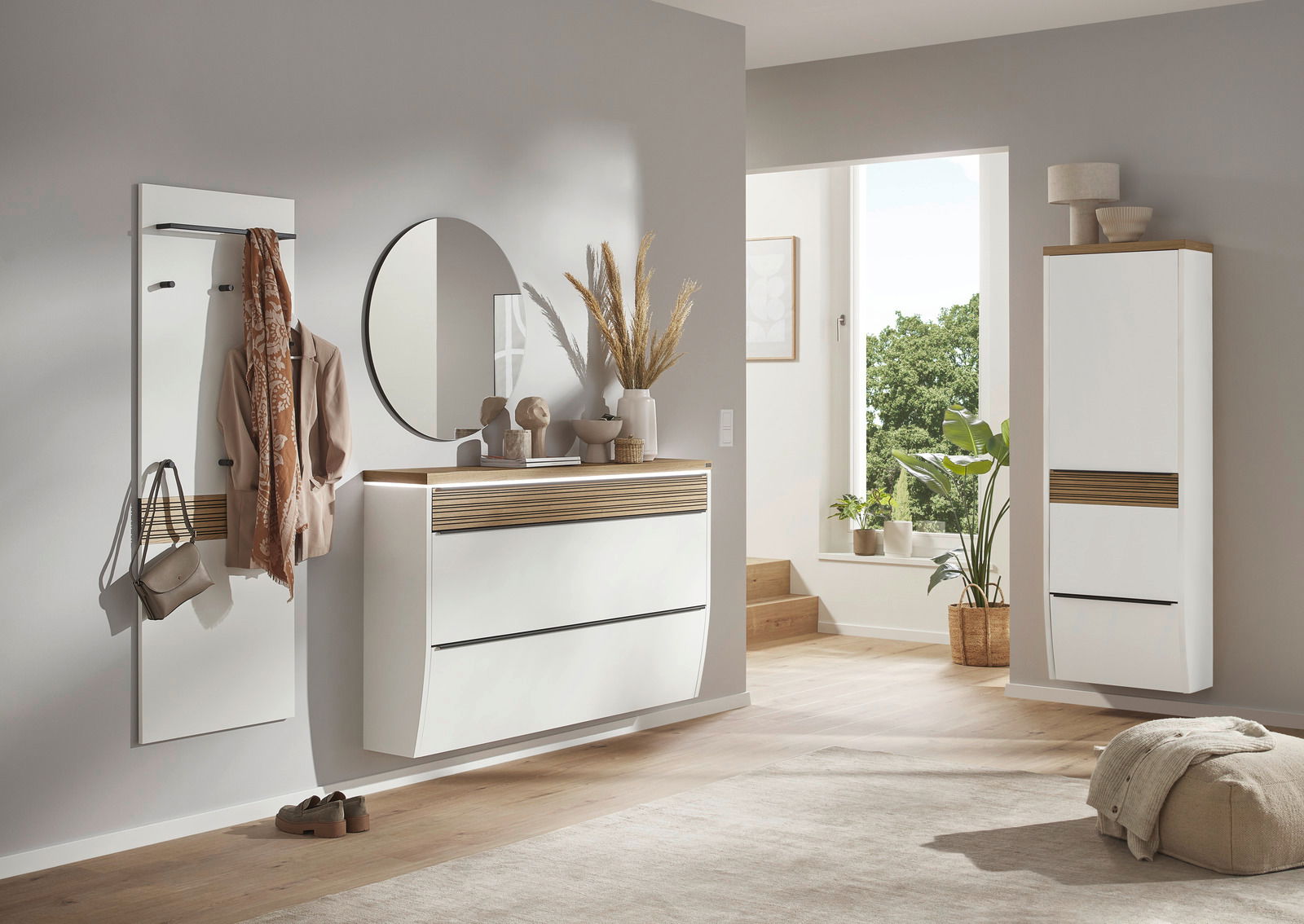 Moderner Eingangsbereich mit weißem Hängeschuhschrank, rundem Spiegel und Garderobenpaneel, seitliche Perspektive.