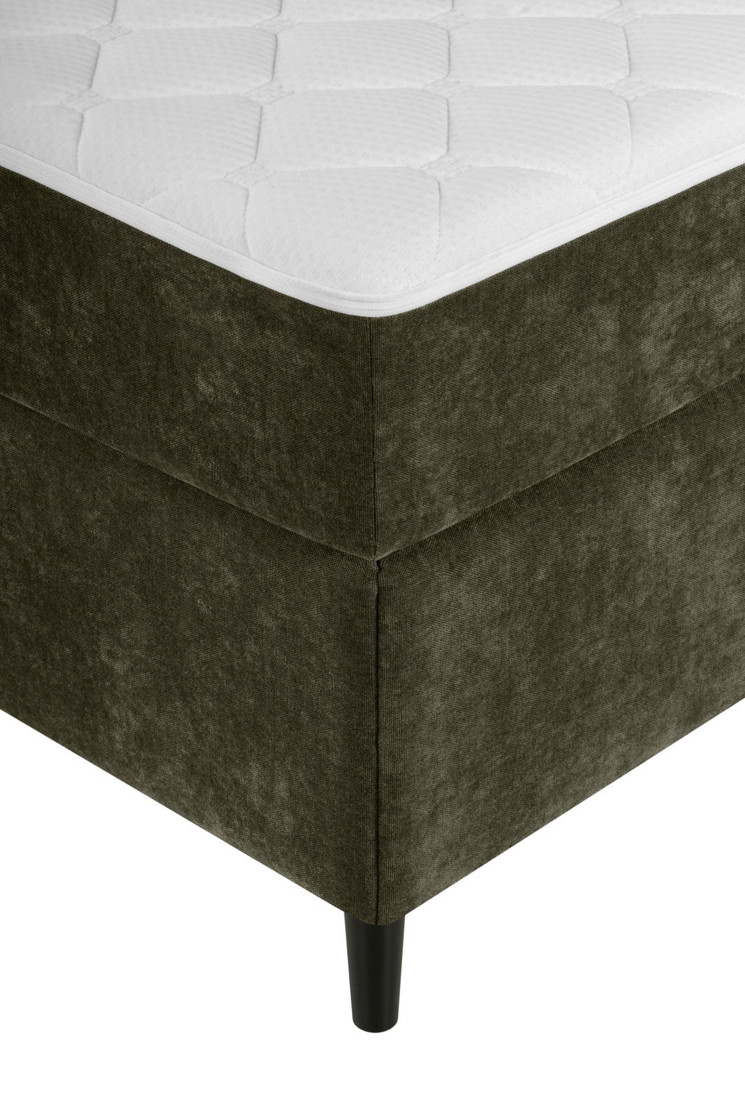 Ecke eines Boxbetts mit dunkelgrünem Stoffbezug und schwarzem Bein, aus der Perspektive von unten links fotografiert.