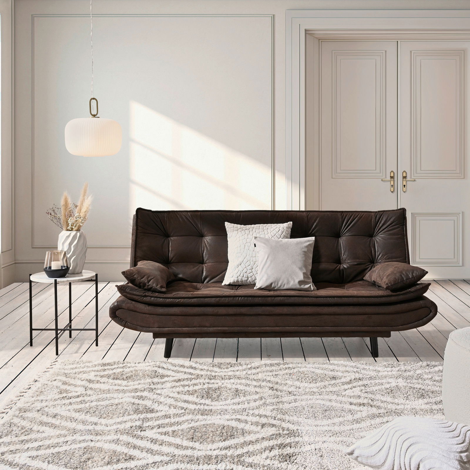 Ti´me Schlafsofa GHOST Braunes Funktionssofa in einem eleganten Wohnzimmer, frontal betrachtet, mit dekorativen Kissen und einem Beistelltisch.