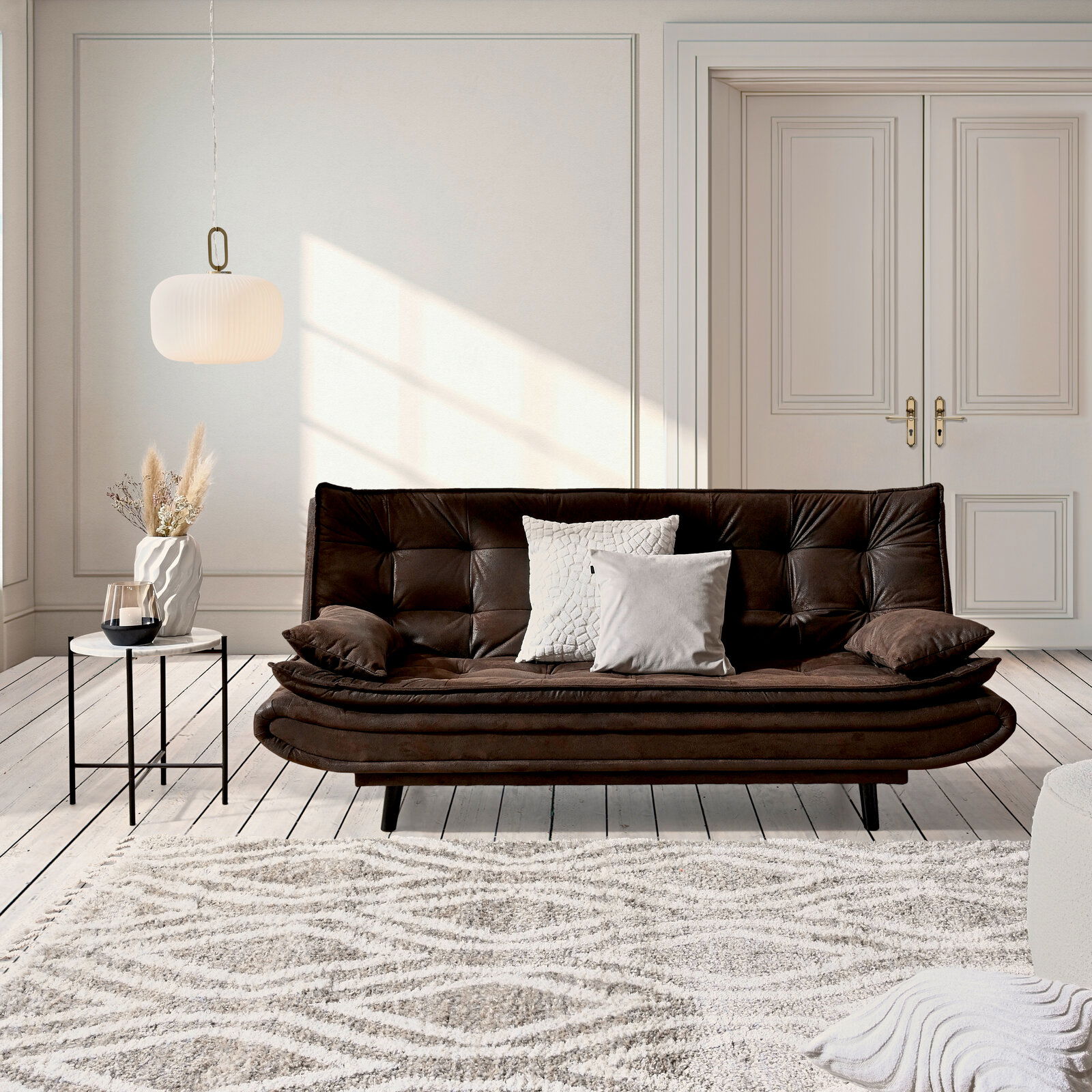 Ti´me Schlafsofa GHOST Braunes Funktionssofa in einem eleganten Wohnzimmer, frontal betrachtet, mit dekorativen Kissen und einem Beistelltisch.