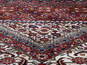 Nahaufnahme eines Orientteppichs mit komplexen Mustern in Rot-, Blau- und Beigetönen, schräg von oben fotografiert.