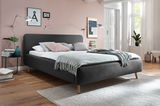 Modernes Polsterbett in Dunkelgrau mit Holzfüßen, seitliche Perspektive, dekoriert mit Kissen und Decke in einem stilvollen Schlafzimmer.