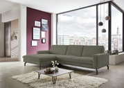 Een moderne longchair-bank in een stijlvolle woonkamer met grote ramen en uitzicht op de stad, gezien vanaf links vooraan.