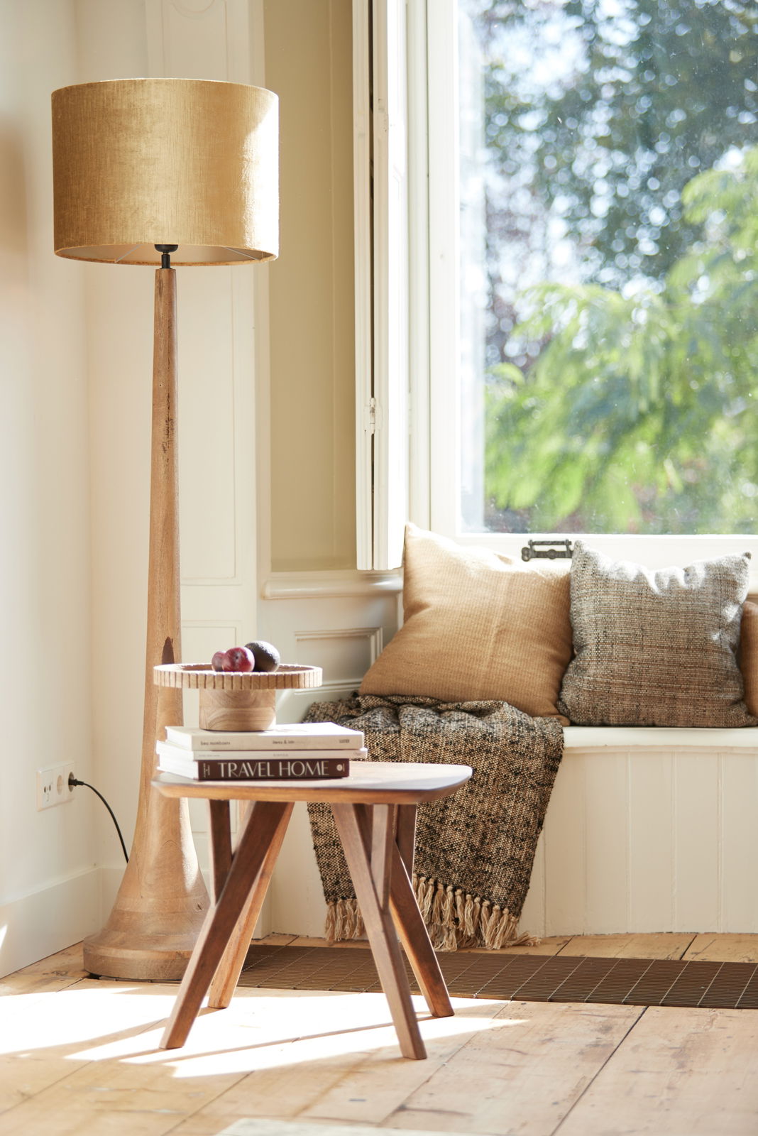 Stehlampe mit zylindrischem, goldenem Lampenschirm in einem gemütlichen Wohnzimmer, seitliche Perspektive