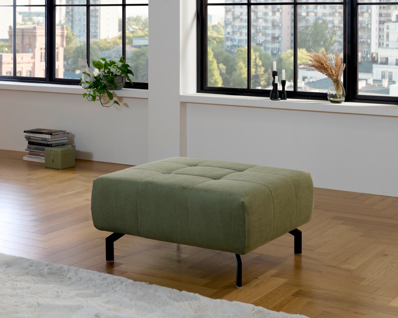 Grüner XL-Hocker in einem modernen Wohnzimmer mit Holzfußboden, seitliche Perspektive.
