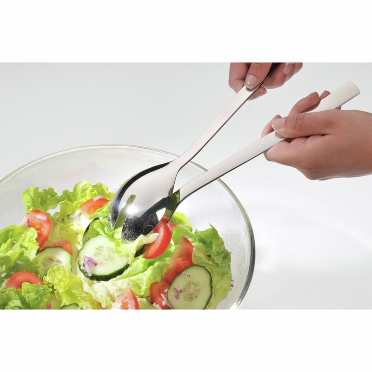 Nahaufnahme eines Servier-Sets mit zwei glänzenden Edelstahl-Salatbestecken, die in einer Schüssel mit frischem Salat verwendet werden.