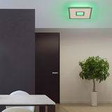 Moderne weiße Deckenleuchte RECESS mit grünem Lichtschein, von unten betrachtet in einem stilvollen Raum mit Tisch, Tür und Pflanze.