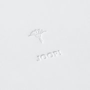 Nahaufnahme eines großen, weißen runden Tabletts mit geprägtem Logo und Blumenmotiv.