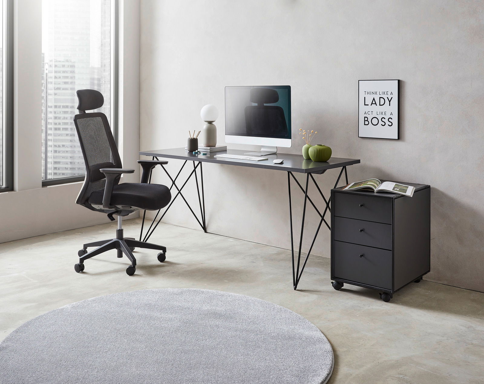 Moderner Schreibtisch mit schwarzem Metallgestell, von der Seite fotografiert, mit Bürostuhl, Computer und Dekorationen in einem hellen Raum.