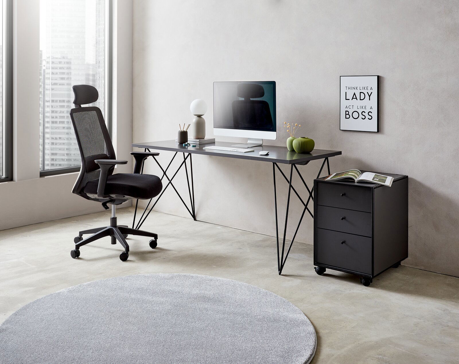 Moderner Schreibtisch mit schwarzem Metallgestell, von der Seite fotografiert, mit Bürostuhl, Computer und Dekorationen in einem hellen Raum.