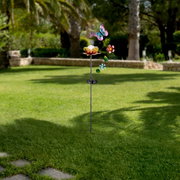 Zonne-lamp in de vorm van een bloem met een vlinder en bloemversiering, geplaatst in een tuin, zijaanzicht