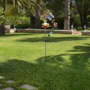 Solarleuchte in Form einer Blume mit Schmetterling und Blumenverzierung, aufgestellt in einem Garten, seitliche Perspektive