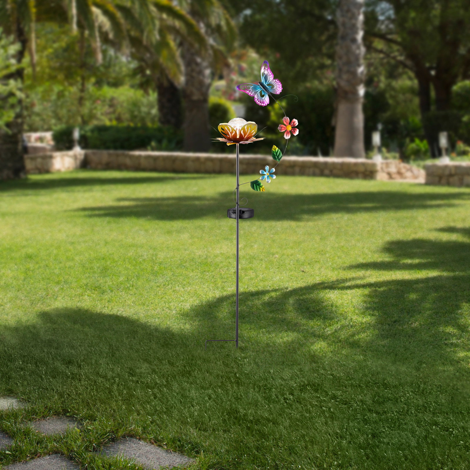 Ambia Garden Zonne-lamp Solarleuchte in Form einer Blume mit Schmetterling und Blumenverzierung, aufgestellt in einem Garten, seitliche Perspektive