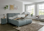 Een bed met verstelbare matrassen in een moderne slaapkamer, gezien vanaf de zijkant