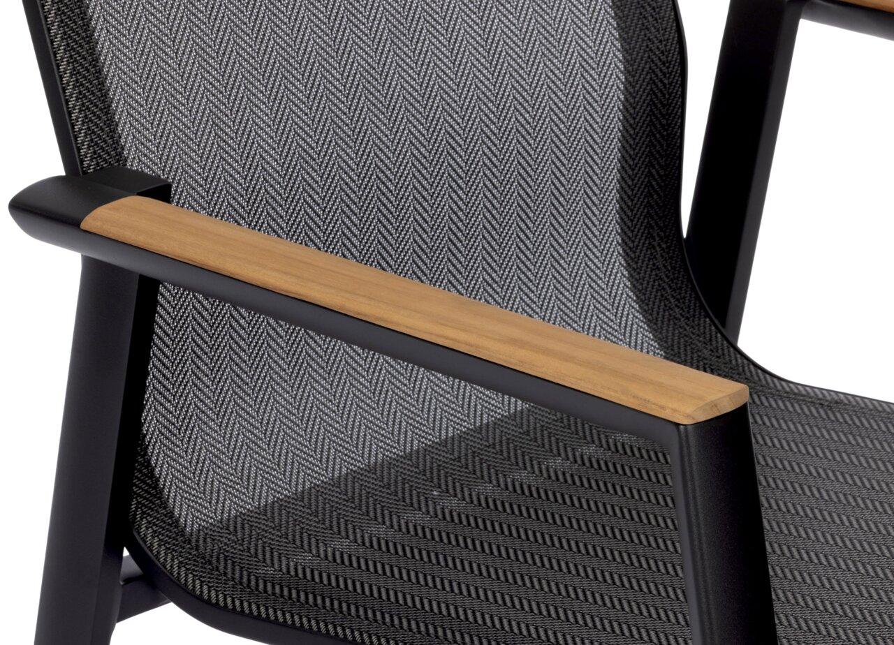 Nahaufnahme eines Stapelstuhls mit schwarzem Rahmen, Holzarmlehnen und gemustertem Stoffbezug, seitliche Perspektive.