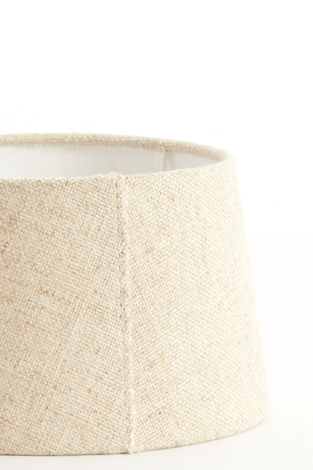 Nahaufnahme eines beige-farbenen, runden Lampenschirms mit texturierter Oberfläche, seitliche Perspektive.