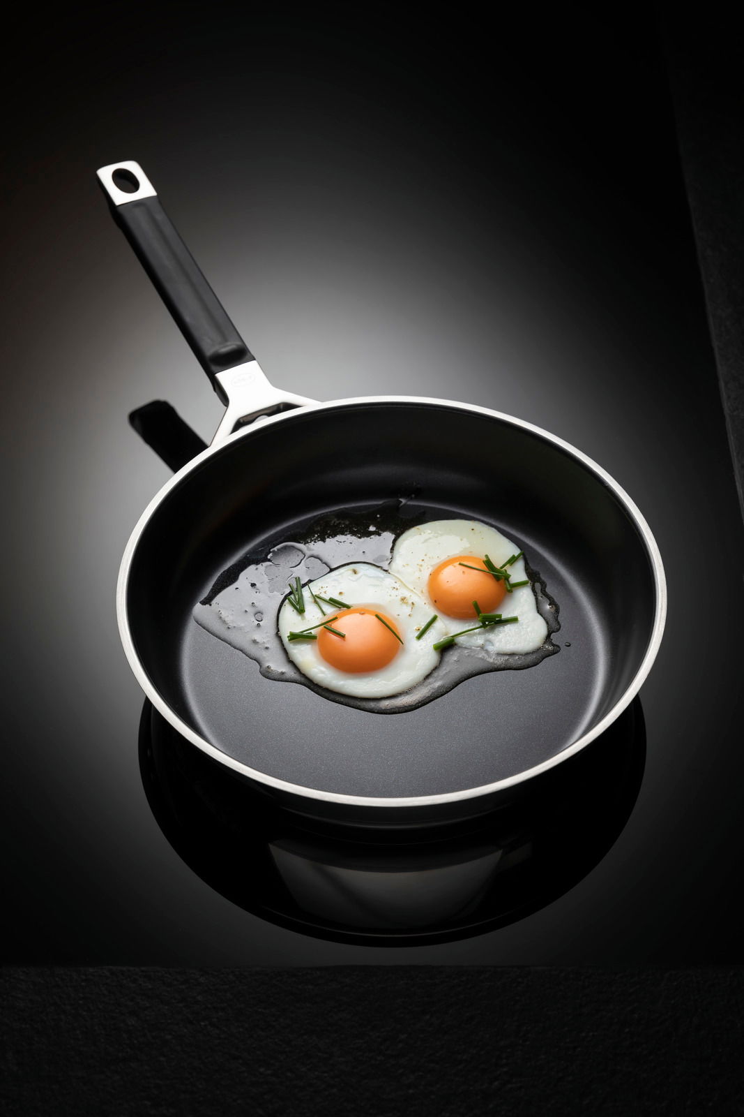 Bratpfanne mit einem Durchmesser von 24 cm, von oben fotografiert, mit zwei Spiegeleiern und Schnittlauch garniert.
