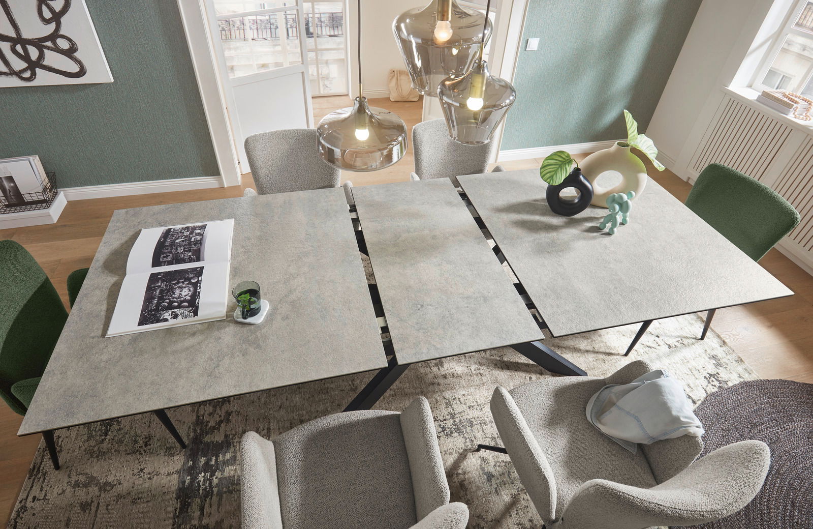 Moderner Esstisch mit grauer Steinoptik-Oberfläche, umgeben von stilvollen Stühlen, aus der Vogelperspektive fotografiert.