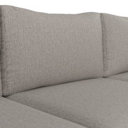 Nahaufnahme eines hellgrauen Stoffsofas mit strukturiertem Bezug und gepolsterten Rücken- und Sitzkissen, Perspektive leicht schräg von vorne auf die Sitzfläche.