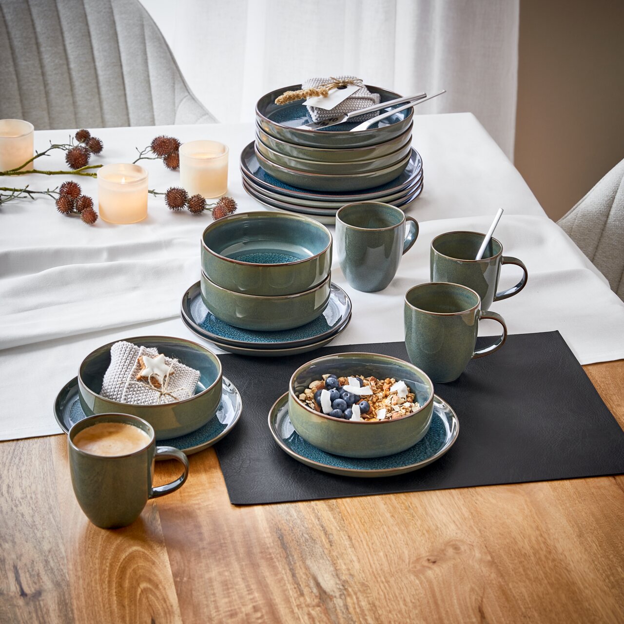 Ontbijtset van 12-delig Breeze in groen keramiek, bestaande uit kopjes, schalen en borden, op een gedekte tafel met kaarsen en decoratie, gefotografeerd vanuit vogelperspectief.