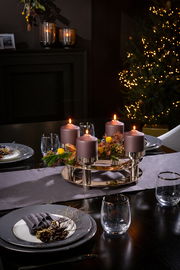 Eleganter 4-flammiger Leuchter mit violetten Kerzen und festlicher Dekoration auf einem gedeckten Tisch, seitliche Perspektive.