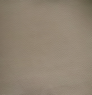 Nahaufnahme einer beige strukturierten Lederoberfläche, die für einen Armlehnstuhl verwendet wird.