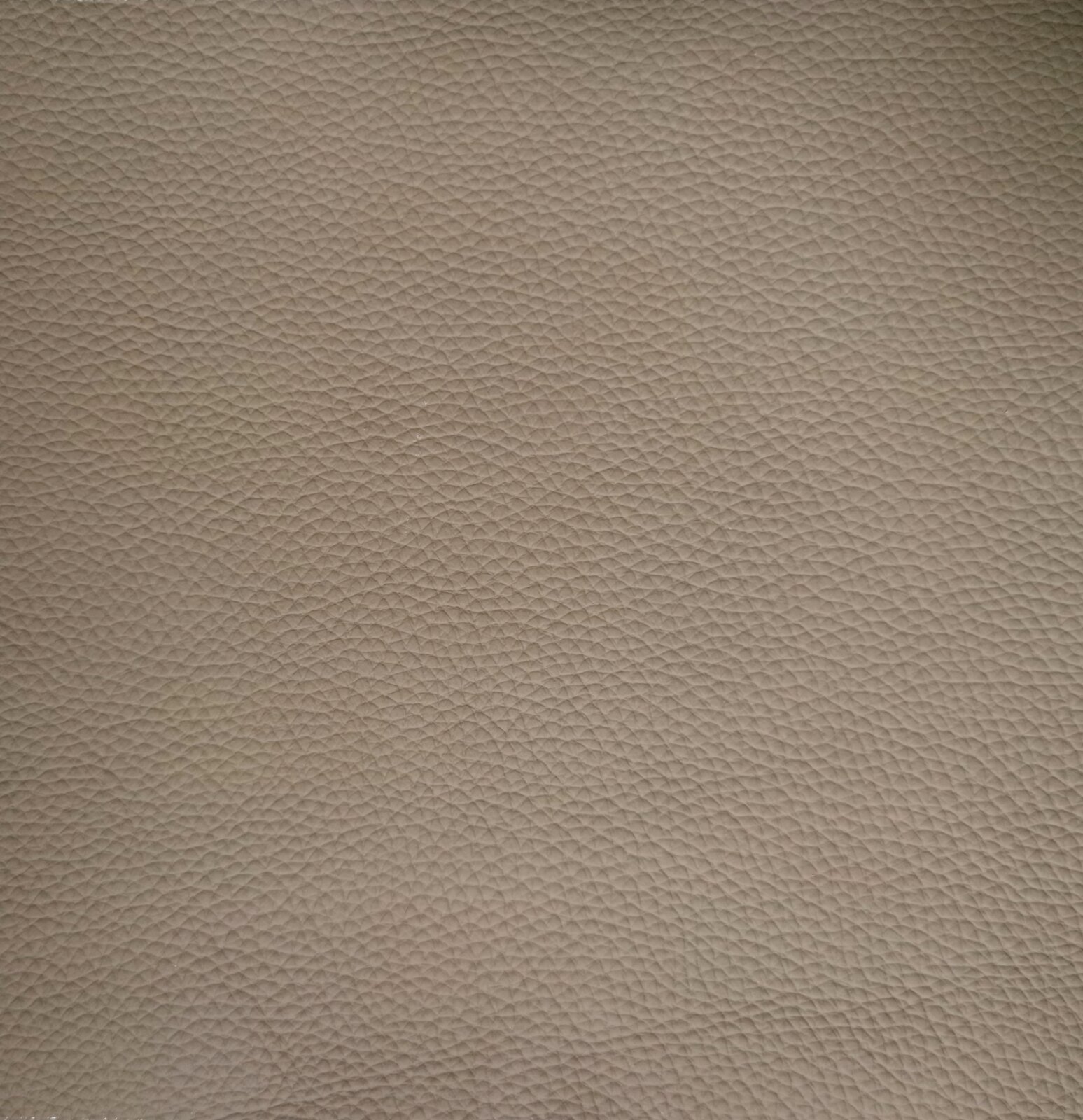 Nahaufnahme einer beige strukturierten Lederoberfläche, die für einen Armlehnstuhl verwendet wird.